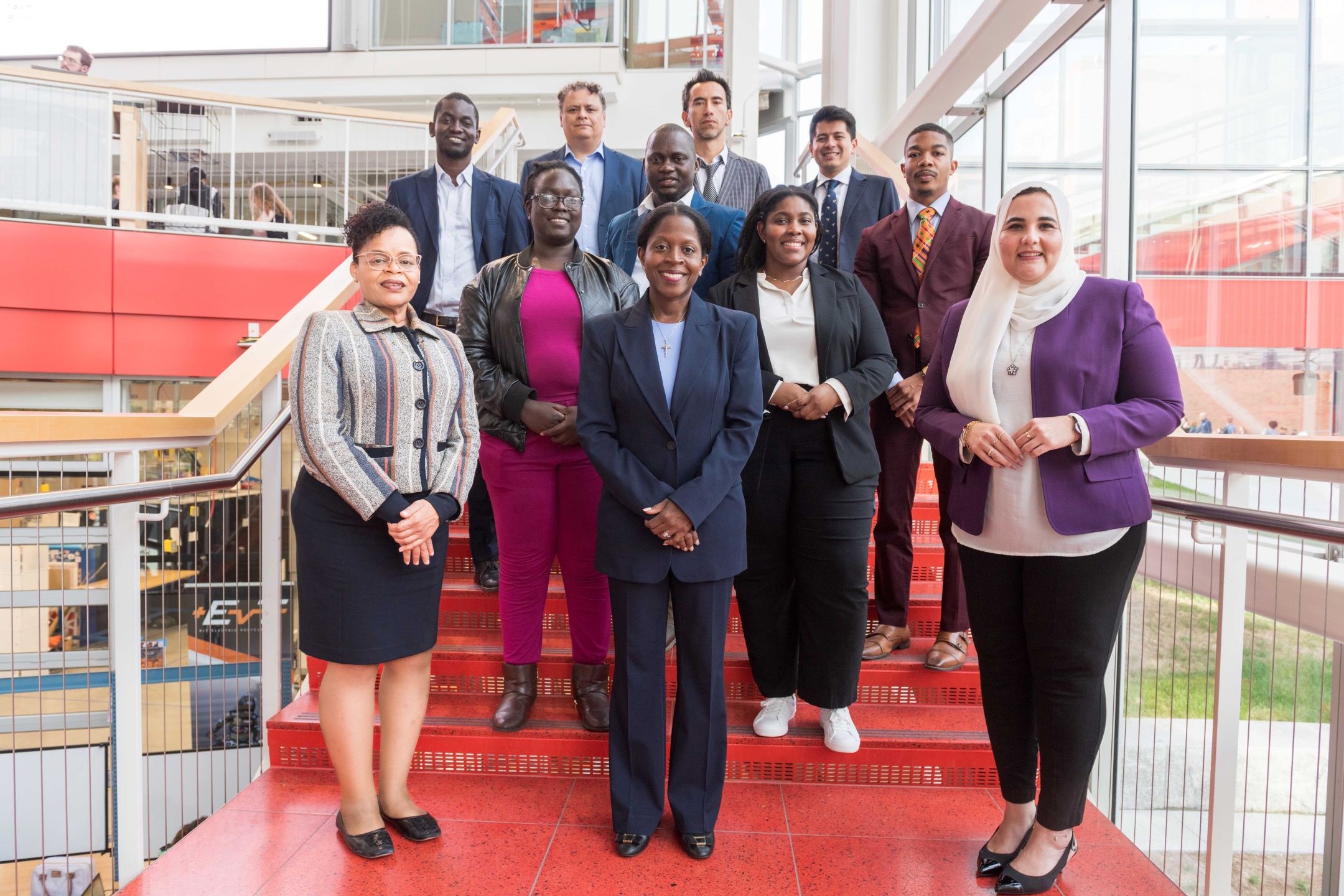 'Group of 11 people in business attire standing on red stairs. '